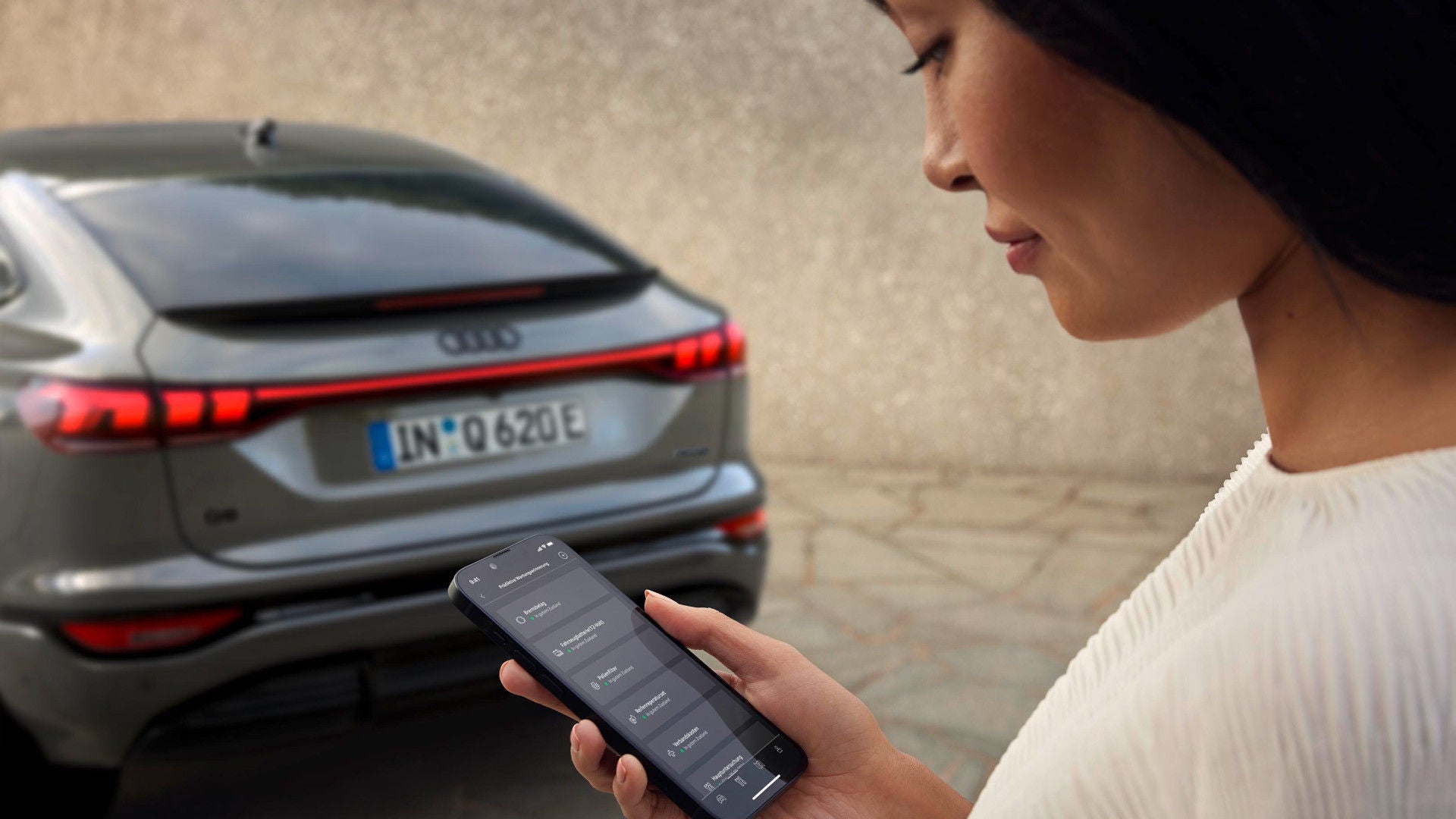 Eine Audi Fahrerin prüft den Zustand ihres Fahrzeugs in der myAudi App. So behält sie jederzeit ausgewählte Verschleißteile im Blick.